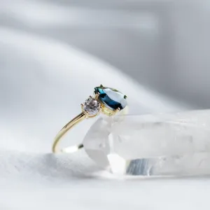 Angled close-up of the COUPLE ring with blue pear sapphire and round diamond