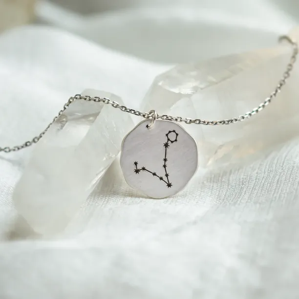 Angled view of the gold STELLARIS necklace and engraved zodiac constellation pendant