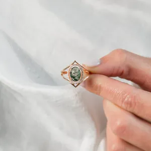 Gold PINIA ring with moss agate and diamonds held between fingers