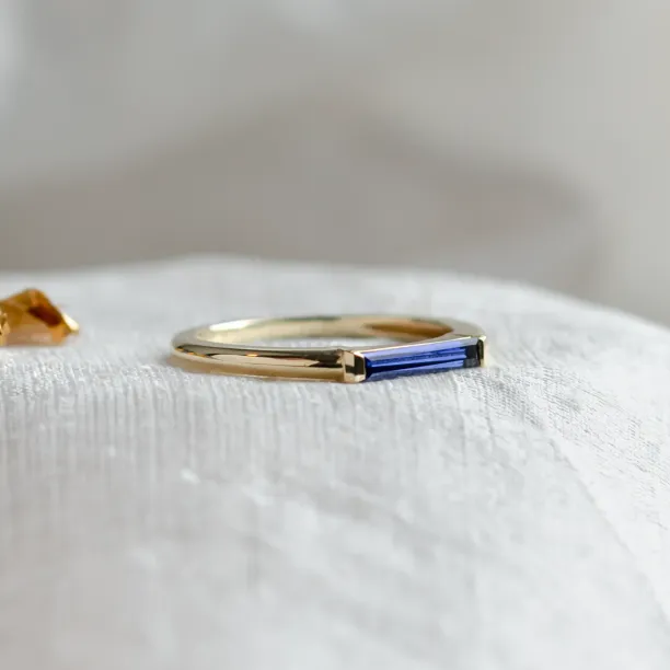 Close-up of the gold CYNTHIA ring and its baguette laboratory sapphire