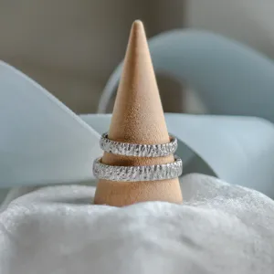 BECCA textured gold wedding rings displayed on a ring cone