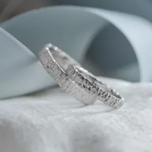 Angled close-up of the unusual texture on BECCA gold wedding rings