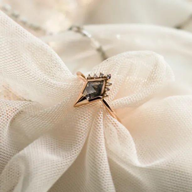 Angled close-up of ADIRA engagement ring with salt and pepper diamond and side diamonds