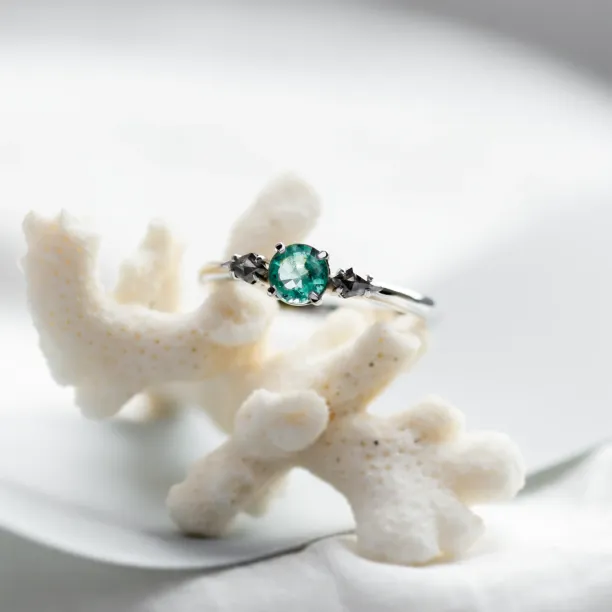 Close-up of a gold ring with emerald and kite salt and pepper diamonds