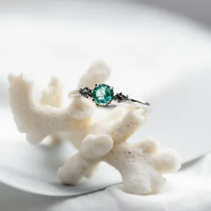 Close-up of a gold ring with emerald and kite salt and pepper diamonds