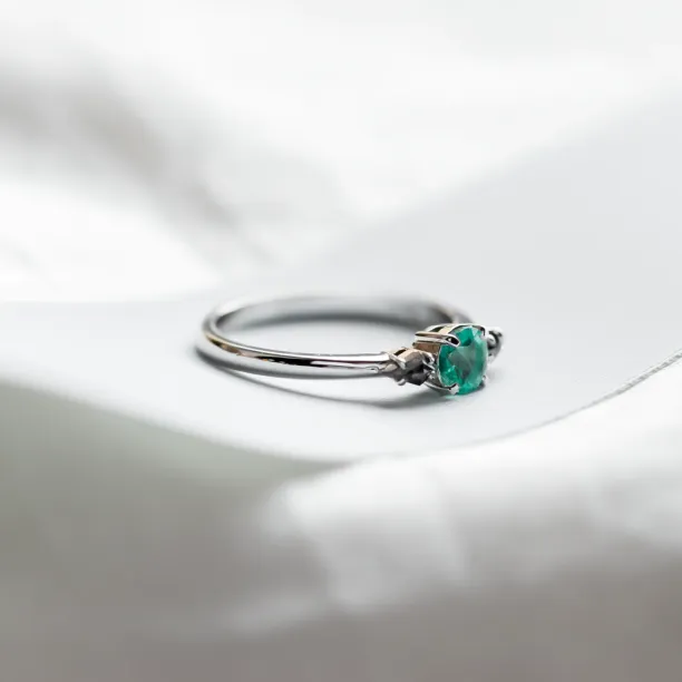 Angled view of the KIM gold ring with emerald and salt and pepper diamonds