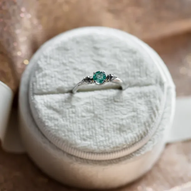 Close-up of the KIM gold ring with emerald and kite salt and pepper diamonds