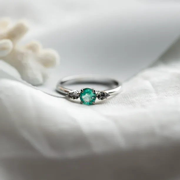 Angled close-up of the KIM gold ring with emerald and salt and pepper diamonds