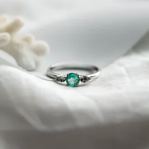 Angled close-up of the KIM gold ring with emerald and salt and pepper diamonds