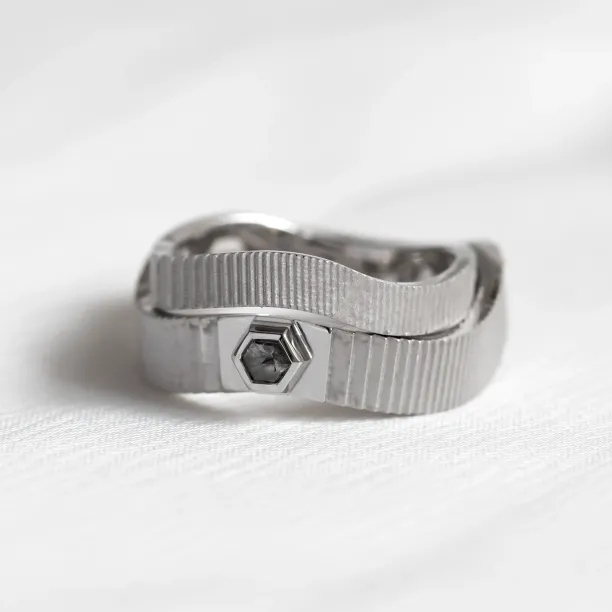 Close-up of JACKLYN wedding rings with textured bands and salt and pepper diamond