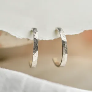 Pair of gold circle earrings with shiny hammered surfaces, angled close-up
