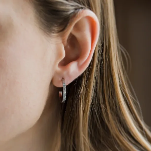 Gold hammered circle earring worn on the ear, close-up detail