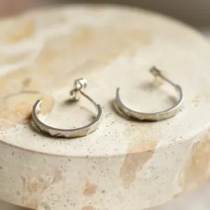 Pair of gold circle earrings showing their hammered surfaces and post fastenings