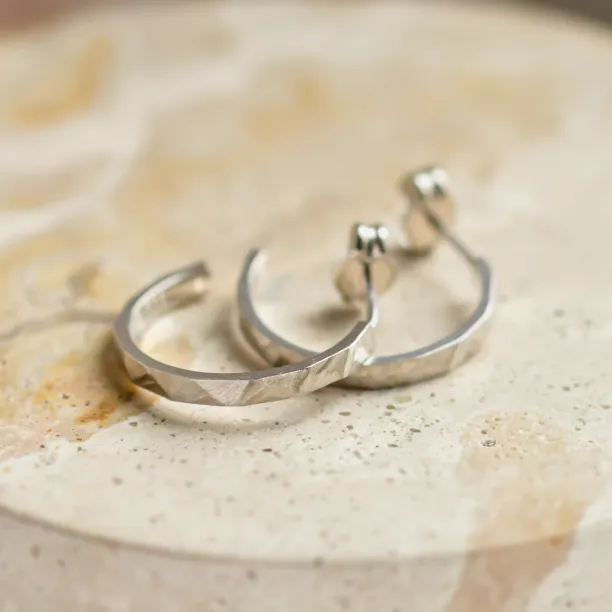 Pair of gold circle earrings in an angled view, showing the hammered surfaces