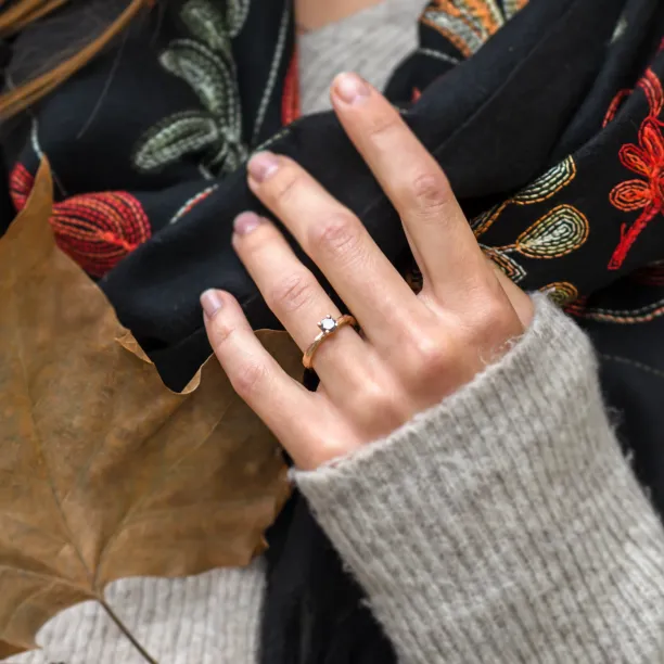 Twig-shaped gold ring with a salt and pepper diamond worn on the hand