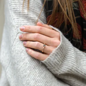 Twig-shaped gold ring with a salt and pepper diamond worn on a finger