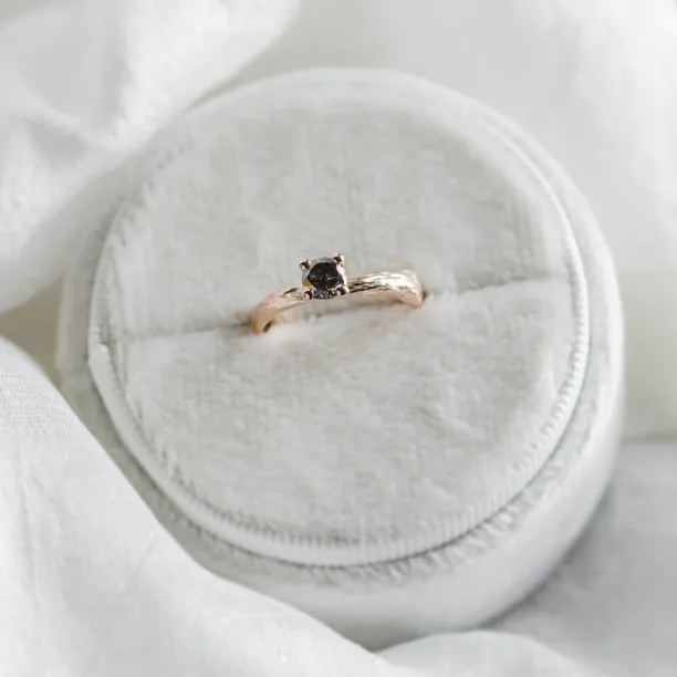 Angled view of the twig-shaped gold ring with a salt and pepper diamond