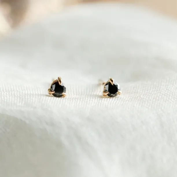 Close-up of DUNCAN gold stud earrings with black diamonds