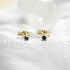 Close-up of DUNCAN gold stud earrings with black diamonds