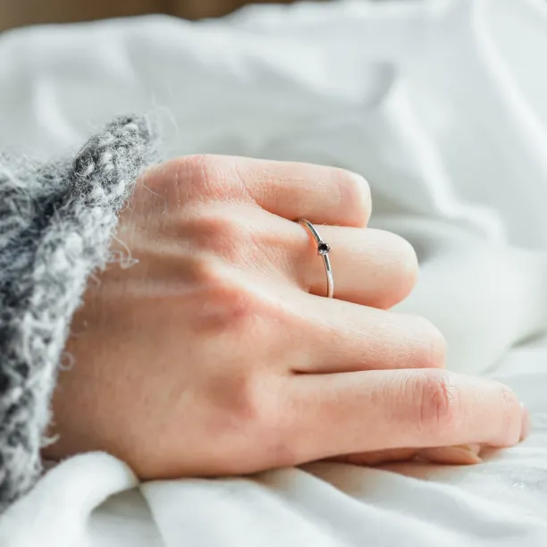 Angled view of a gold ring with a black diamond worn on the hand
