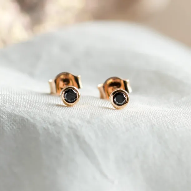 Close-up of DARCY gold stud earrings with black diamonds