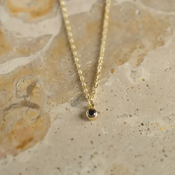 Angled view of the gold necklace and black diamond bezel pendant