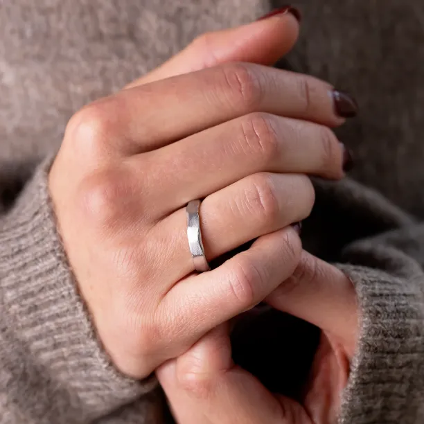 DANTE gold wedding band with a torn paper edge worn on the hand