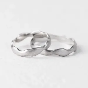 Angled view of the GOCCIO pair of irregular wedding rings
