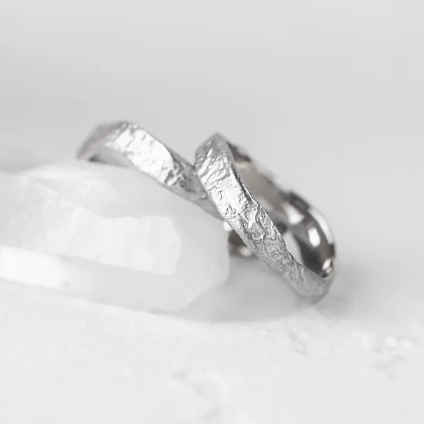 Angled close-up of MUSK gold wedding bands with moon-surface texture