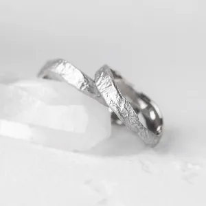 Angled close-up of MUSK gold wedding bands with moon-surface texture