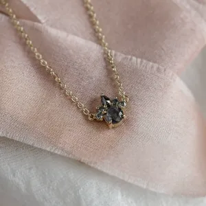 Angled close-up of the gold ASTRAL necklace pendant with gray salt and pepper diamonds