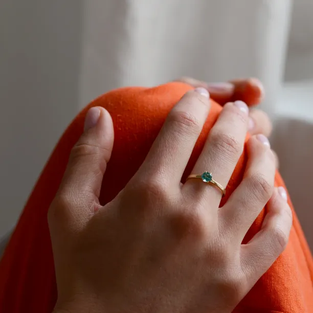 Gold engagement ring with emerald JADE worn on the hand