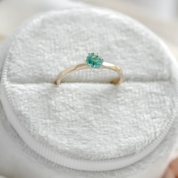 Close-up of the gold engagement ring with emerald JADE and prong setting