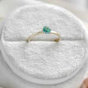 Close-up of the gold engagement ring with emerald JADE and prong setting