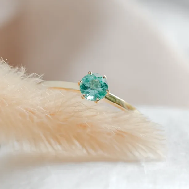 Close-up of the emerald and prong setting on the gold JADE ring