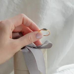 Gold hexagon salt and pepper diamond engagement ring held between fingers