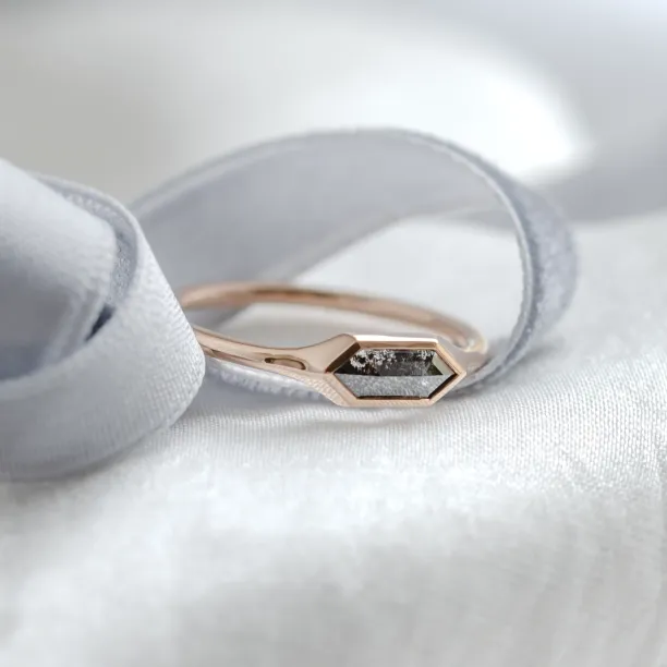 Angled close-up of gold engagement ring with a hexagon salt and pepper diamond