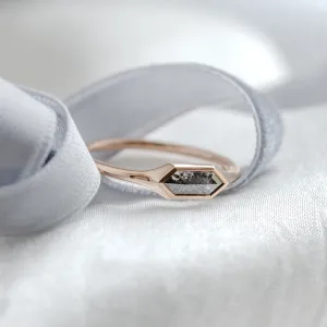 Angled close-up of gold engagement ring with a hexagon salt and pepper diamond
