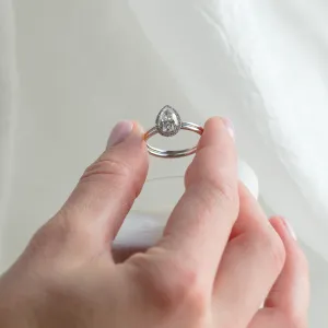 KIMBER pear-shaped moissanite engagement ring held between fingers