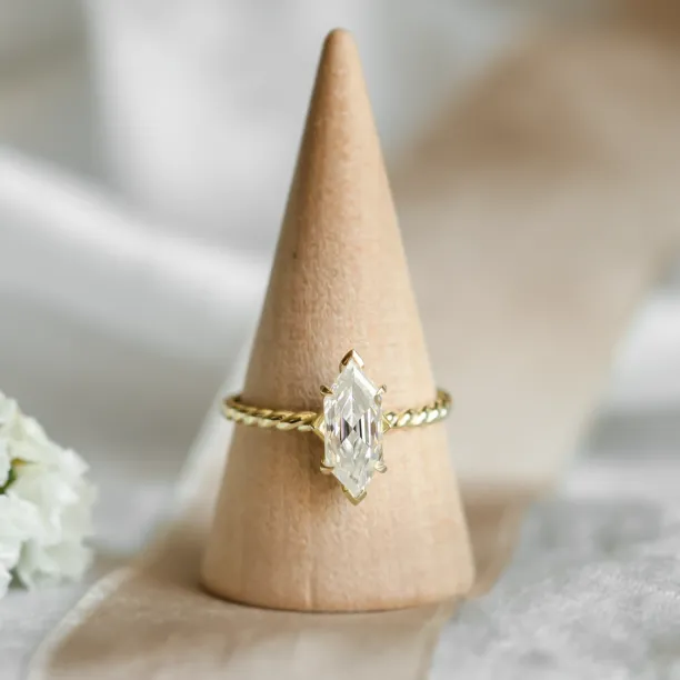Gold SALEM ring with hexagon moissanite displayed on a ring stand