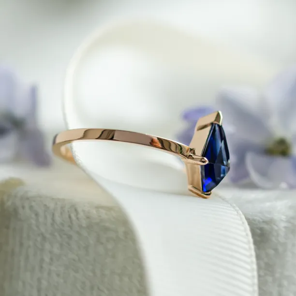 Side view of the KODA gold ring with its kite-shaped blue sapphire
