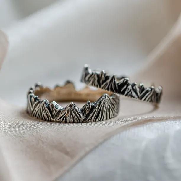 Angled view of SILVRETTA wedding rings with mountain relief and black rhodium