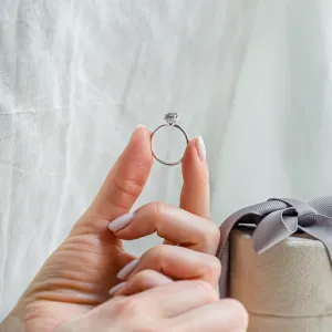 TANAQUIL salt and pepper diamond engagement ring held between fingers