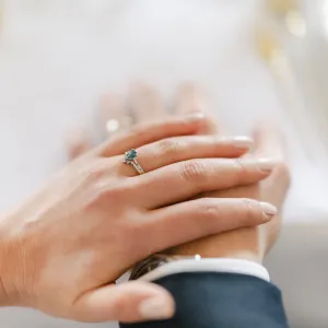 Gold ring with London blue topaz worn on a hand