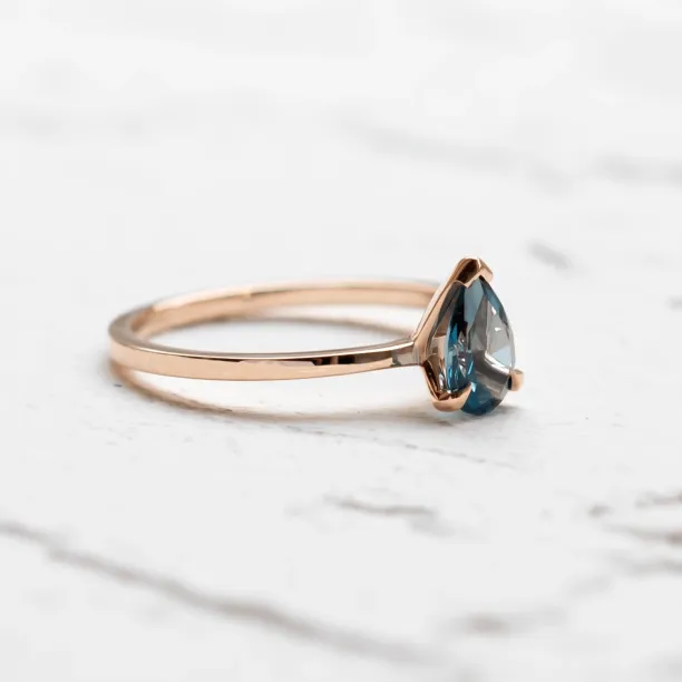 Side view of a gold ring with London blue topaz