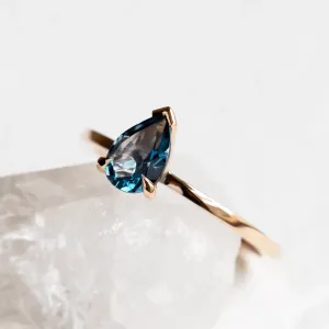 Angled close-up of the gold DROP ring with London blue topaz