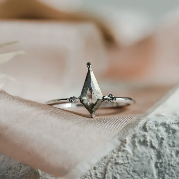 Close-up of the VALENTINO gold engagement ring with a kite-shaped salt'n'pepper diamond