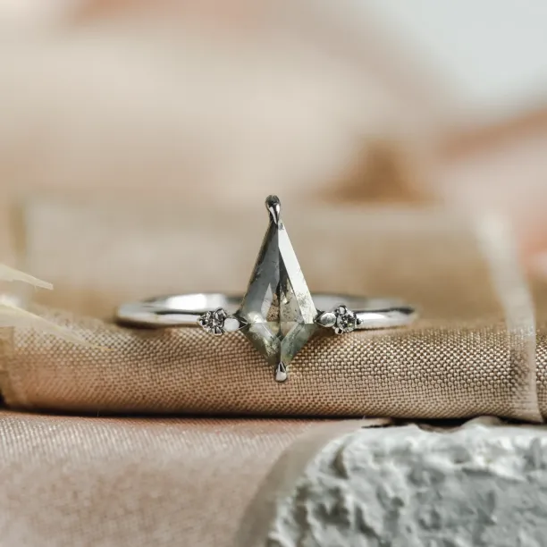 Close-up of the VALENTINO gold engagement ring with side diamonds and a salt'n'pepper diamond