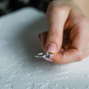 Zlatý prsten ELIZABETH s modrým safírem a diamanty držený v ruce