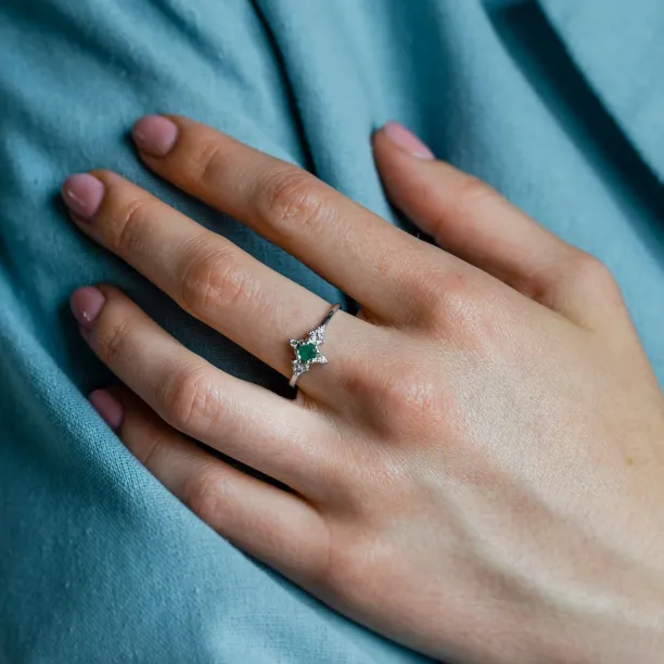 Gold emerald ring with diamonds worn on the hand